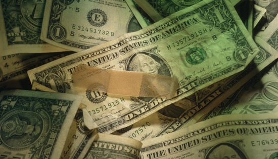 dollar bills spread out with a single band-aid sitting on one