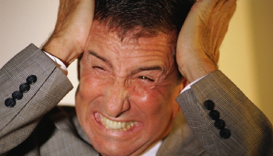 man in suit making angry face and holding his head