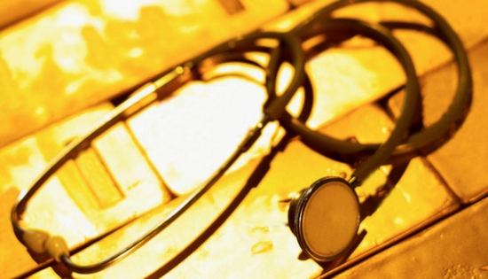 Stethoscope sitting on top of a pile of gold bullion