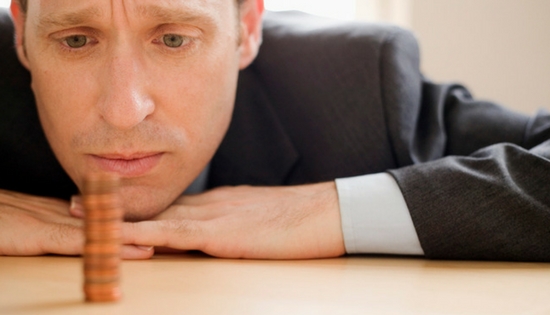 man looking sadly at stack of pennies