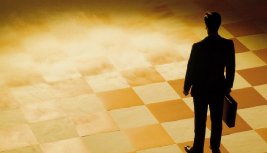 business man standing on checkered board that is dissolving