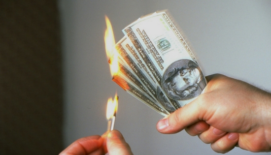 someone lighting a handful of cash on fire with a match